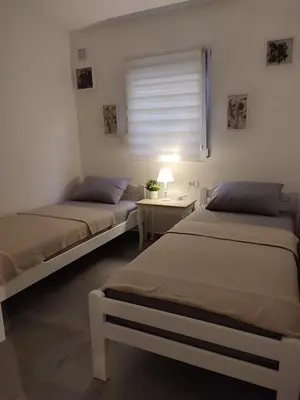 two beds in a room with a table and a window at Sayohat Apartments in Dobra Voda