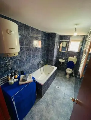 a blue tiled bathroom with a tub and a toilet at House of peace in Podgorica
