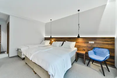 two beds in a room with a desk and a blue chair at Hotel Vladimir in Budva