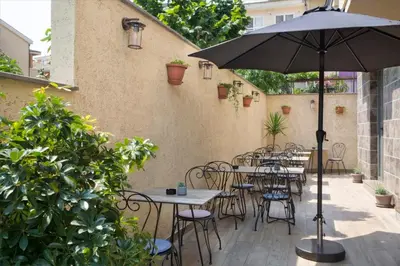 an outdoor patio with tables and chairs and an umbrella at Hotel Vladimir in Budva