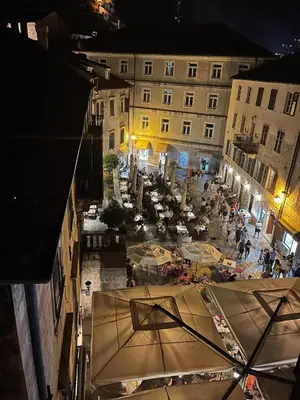 a view of a courtyard with tables and umbrellas at night at Cozy 2 Bedroom Apartment in Antique Bizanti Palace in Kotor