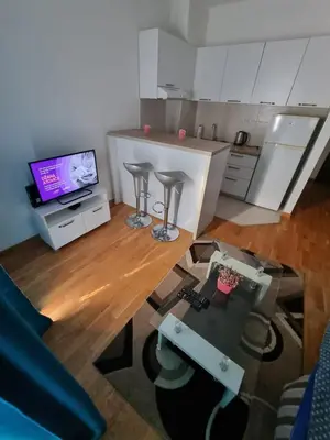 a living room with a table and a kitchen with a tv at Adrianna apartment City kvart in Podgorica