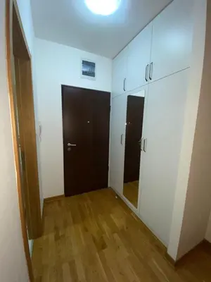 an empty room with white cabinets and a wooden floor at Adrianna apartment City kvart in Podgorica