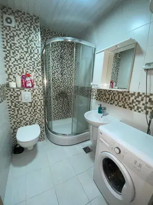 a bathroom with a shower and a washing machine in it at Adrianna apartment City kvart in Podgorica