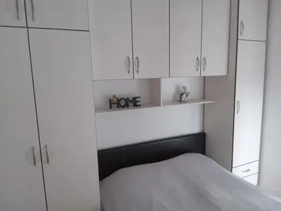 a bedroom with white cabinets and a bed at Flat Iva in Podgorica