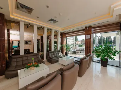 a living room with couches and tables and windows at Hotel New Star in Podgorica
