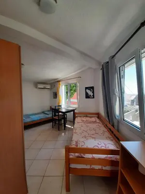 a bedroom with a bed and a table and a window at Милый гостевой апартамент in Bar