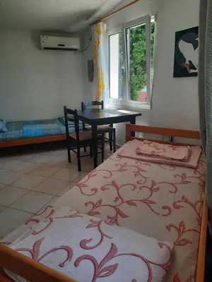 a bedroom with two beds and a table and a window at Милый гостевой апартамент in Bar