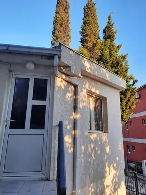 a small house with a white door and trees at Милый гостевой апартамент in Bar