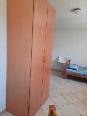 a large wooden cabinet in a room with a bed at Милый гостевой апартамент in Bar
