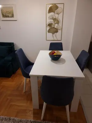 a white table with chairs and a bowl of fruit on it at Big apartment in Podgorica