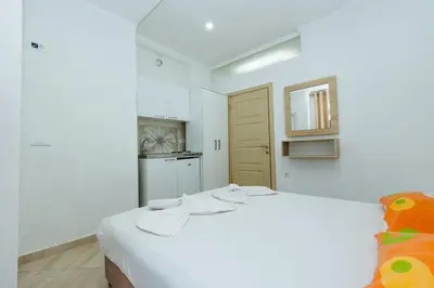 a white room with a bed and a kitchen at Flori Apartments in Ulcinj