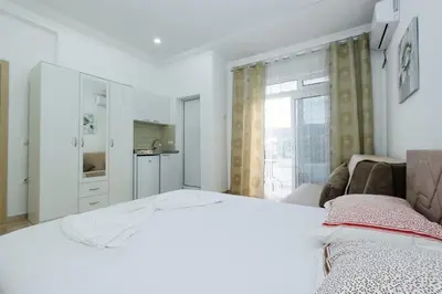 a white bedroom with a bed and a window at Flori Apartments in Ulcinj