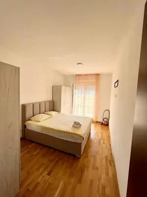 a bedroom with a bed and a wooden floor at Z apartment in Podgorica