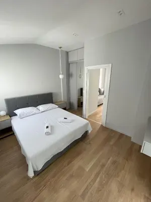 a white bedroom with a large white bed and wooden floors at Lungomare Apartments in Petrovac na Moru