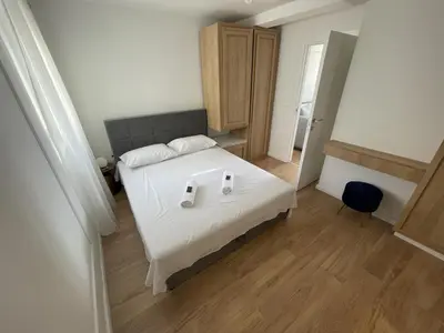 a bedroom with a white bed and a blue chair at Lungomare Apartments in Petrovac na Moru