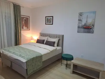 a bedroom with a bed and a green stool in it at Apartman City kvart in Podgorica