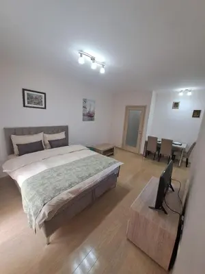a bedroom with a large bed and a table and a desk at Apartman City kvart in Podgorica