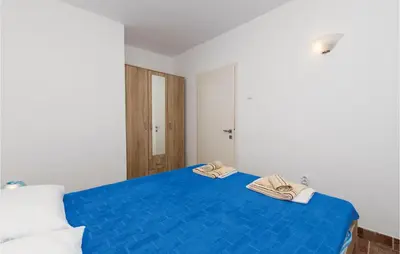 a bedroom with a blue bed with two towels on it at Nice Apartment In Utjeha With Kitchen in Utjeha