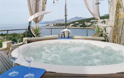 a bath tub on a balcony with two wine glasses at Nice Apartment In Utjeha With Kitchen in Utjeha
