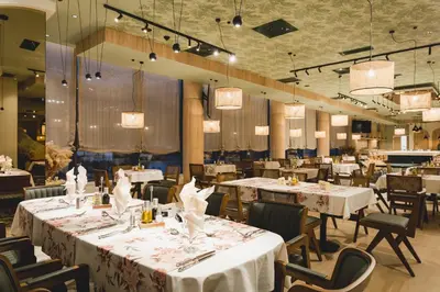 a restaurant with white tables and chairs and lights at Hotel Aurel Coast in Kotor