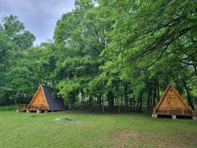 two small wooden houses in a field with trees at Private Camp - Wolf & Sheep - 4 bungalows- 8 person in Podgorica