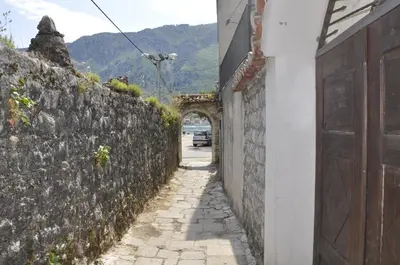 an alley with a stone wall and a car driving down a street at Apartments Ivanišević in Kotor