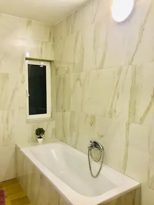a white bathroom with a tub and a window at Apartments Ivanišević in Kotor