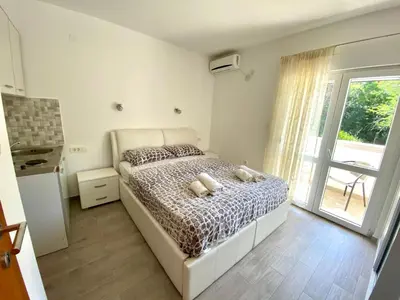 a bedroom with a bed and a large window at Apartments Popović in Budva