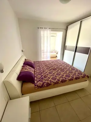 a bedroom with a bed with a purple blanket at Apartments Popović in Budva