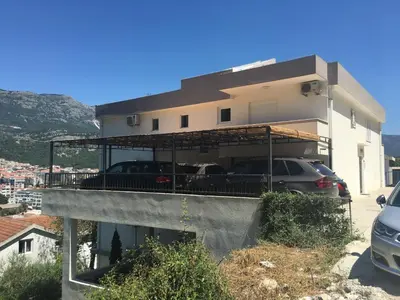 a house with two cars parked on a balcony at Apartments Popović in Budva