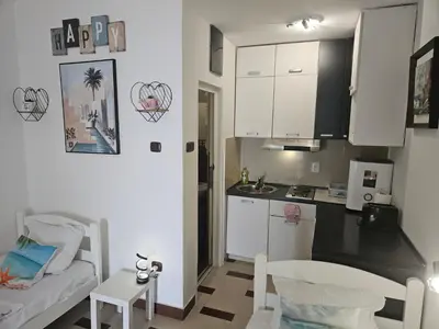 a small kitchen with white cabinets and a table at Seaview, just across the beach, Bečići in Becici
