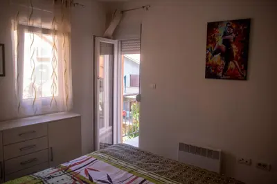 a bedroom with a bed and a window and a painting at Apartment Marija in Podgorica