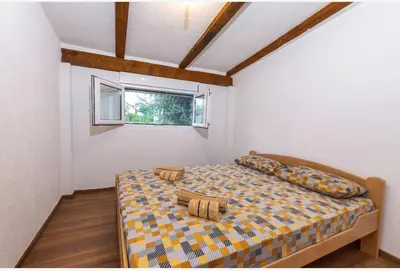 a bedroom with a bed with pillows and a window at Apartman Maslina in Podgorica