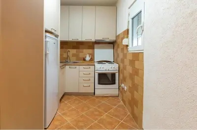 a kitchen with white cabinets and a stove top oven at Apartman Maslina in Podgorica