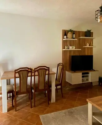 a living room with a table and chairs and a television at Apartman Maslina in Podgorica