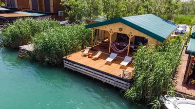 a wooden deck with chairs and a playground on the water at Sojenica Tamara in Ulcinj