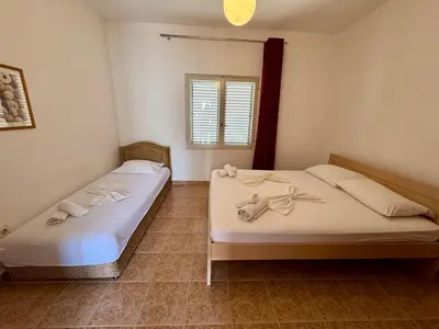 two twin beds in a room with a window at Apartments Marniković in Ulcinj