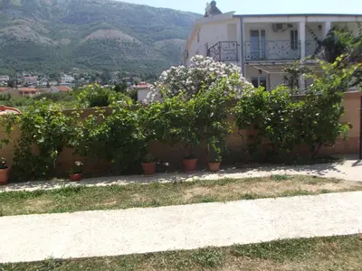 a retaining wall with potted plants in front of a house at Apartmani Stojanović in Sutomore