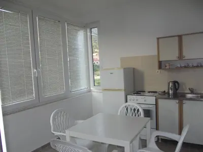 a kitchen with a table and a white table and chairs at Apartmani Stojanović in Sutomore