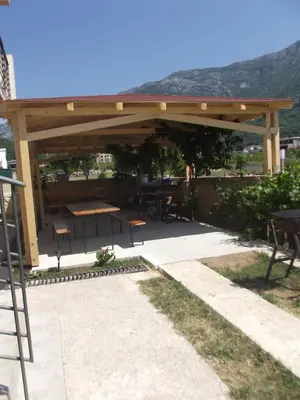 a wooden pavilion with a picnic table and tables at Apartmani Stojanović in Sutomore