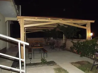 a wooden pergola on a patio at night at Apartmani Stojanović in Sutomore