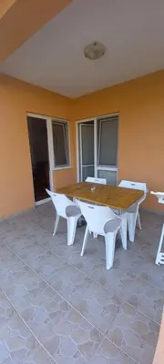 a wooden table and white chairs in a room at Apartmani Stojanović in Sutomore
