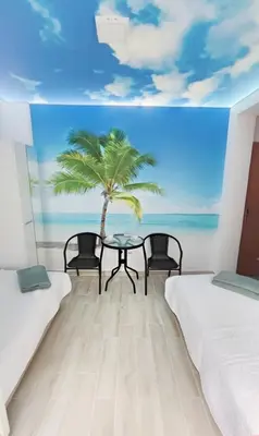 a room with two beds and a table with a palm tree at Mini Candy central location Bečići in Becici