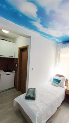 a bedroom with a white bed with a blue ceiling at Mini Candy central location Bečići in Becici