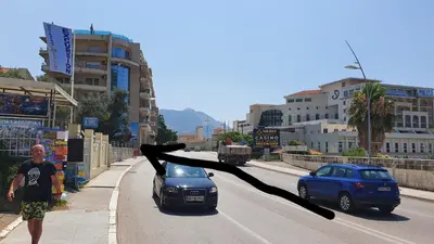 a man walking down a street with a bird flying over a car at Mini Candy central location Bečići in Becici
