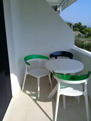 a white table and two green chairs in a room at HM Apartmani in Bar