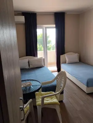 a room with two beds and a table and a window at HM Apartmani in Bar