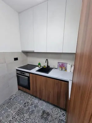 a kitchen with white cabinets and a sink and a stove at Fantastic new centre apartment in Podgorica