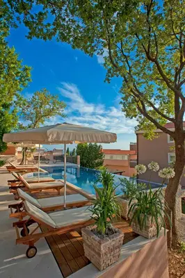 a group of lounge chairs and an umbrella next to a pool at Harmonia Bungalows & Pool in Sveti Stefan